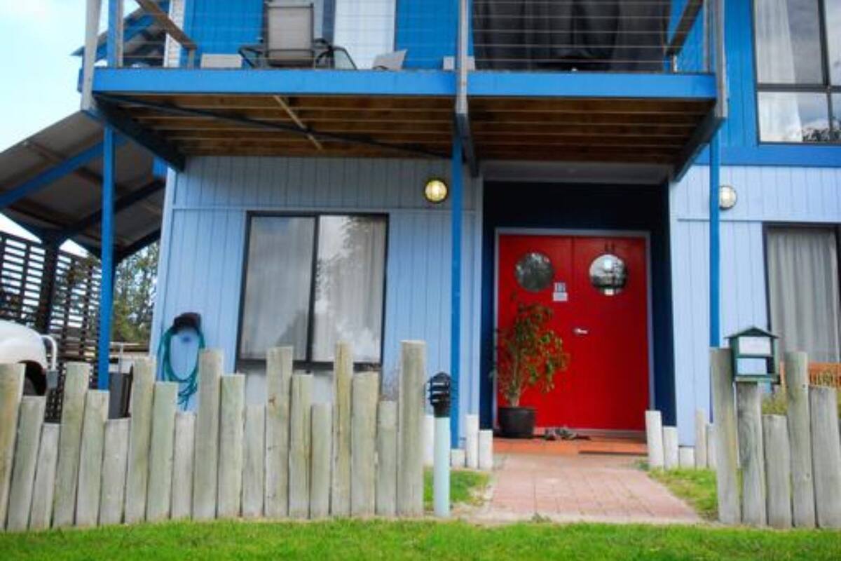 A two-story building with a red door, a balcony on the upper floor, and a wooden fence in front.