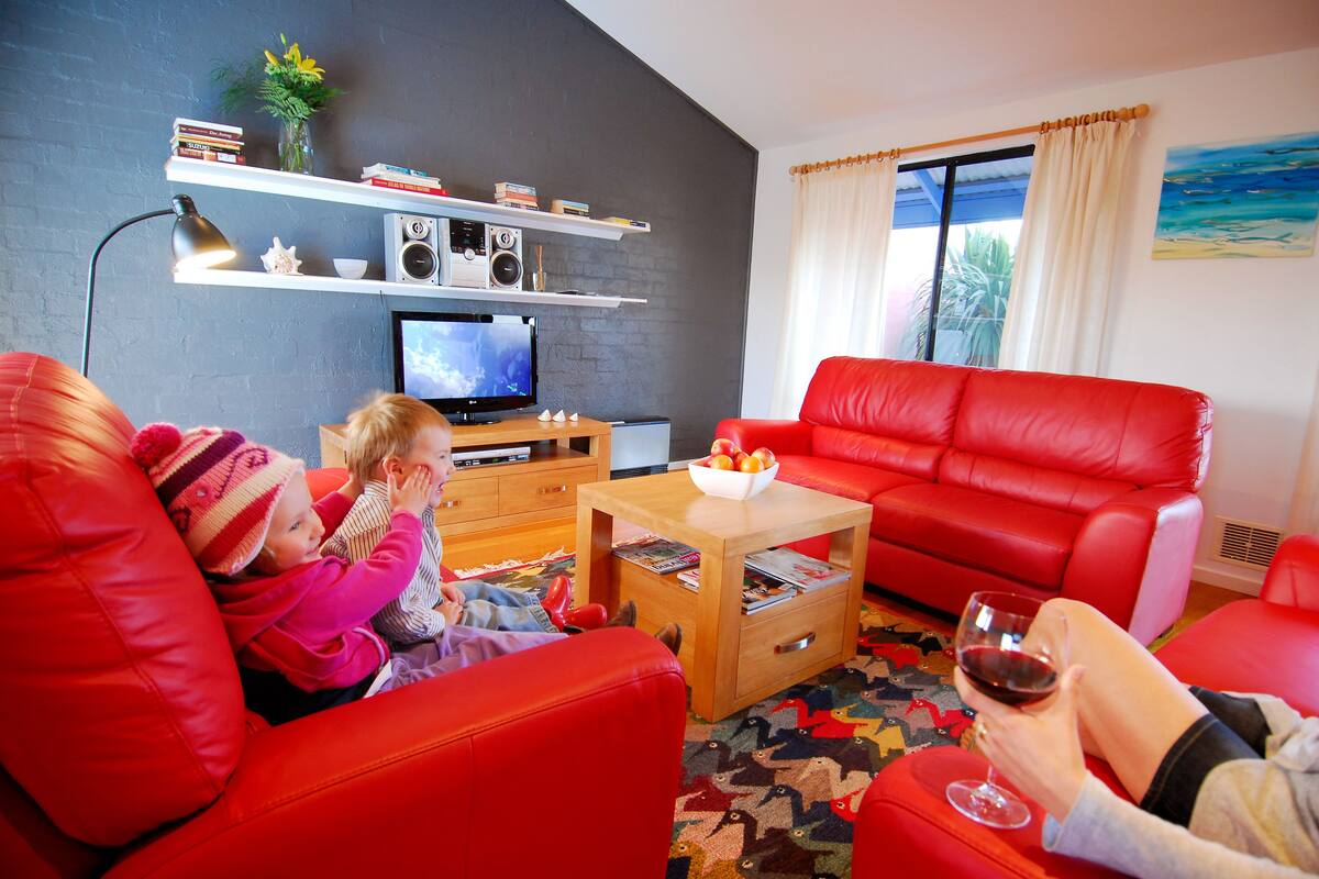 A living room with red furniture, a television, and a bookshelf.