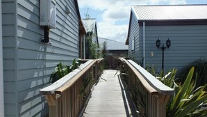 A narrow wooden pathway between two buildings with a metal roof. - Cranford Cottages And Motel (Christchurch)