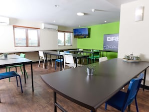 A conference room with tables, chairs, and a large screen. - Ibis Budget Perth Airport (Redcliffe)