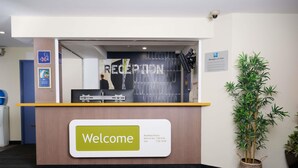 A reception desk with a 'Welcome' sign, a plant, and a 'Managers on Duty' sign. - Ibis Budget Perth Airport (Redcliffe)