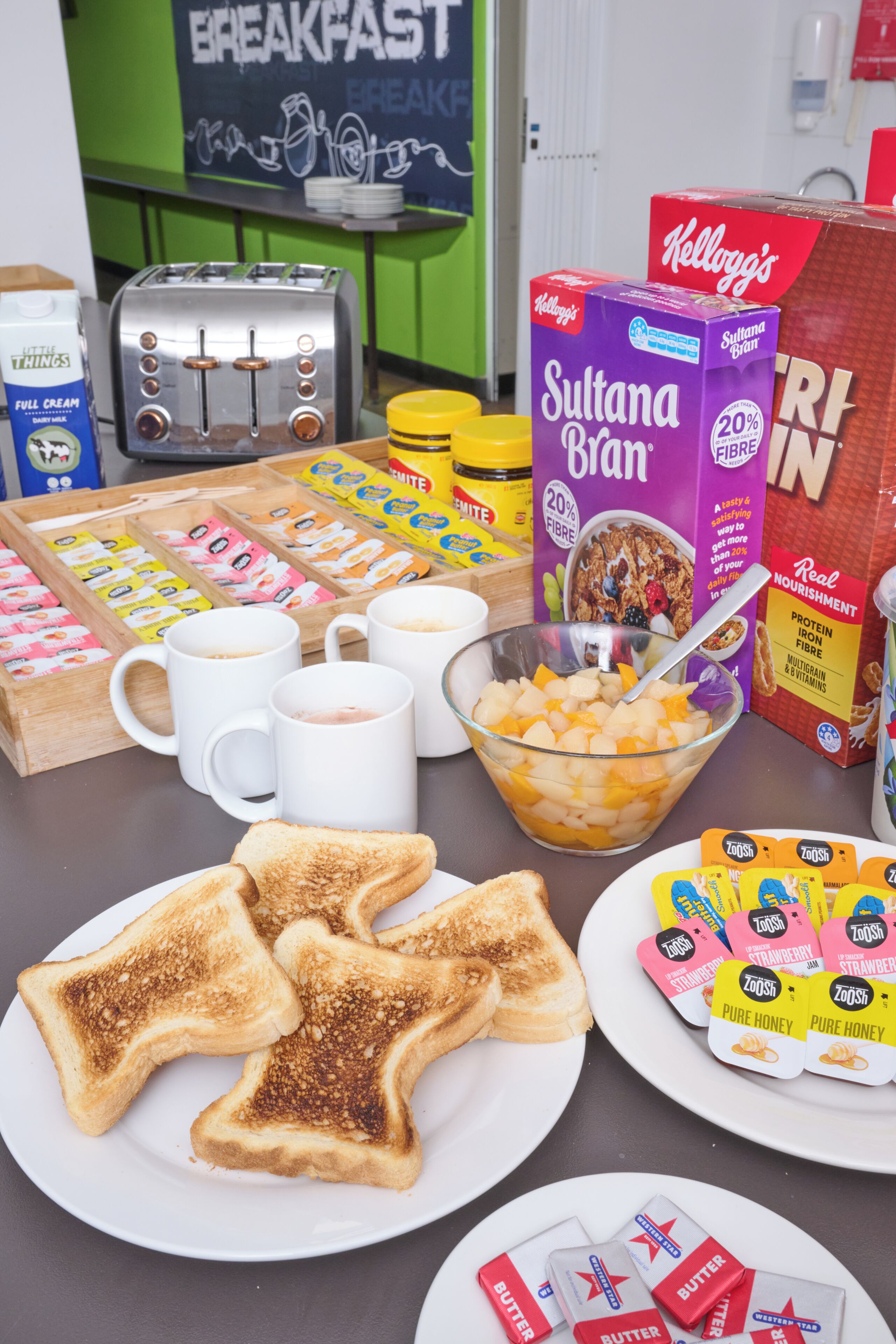 A breakfast setup with toast, cereal, milk, and various spreads.