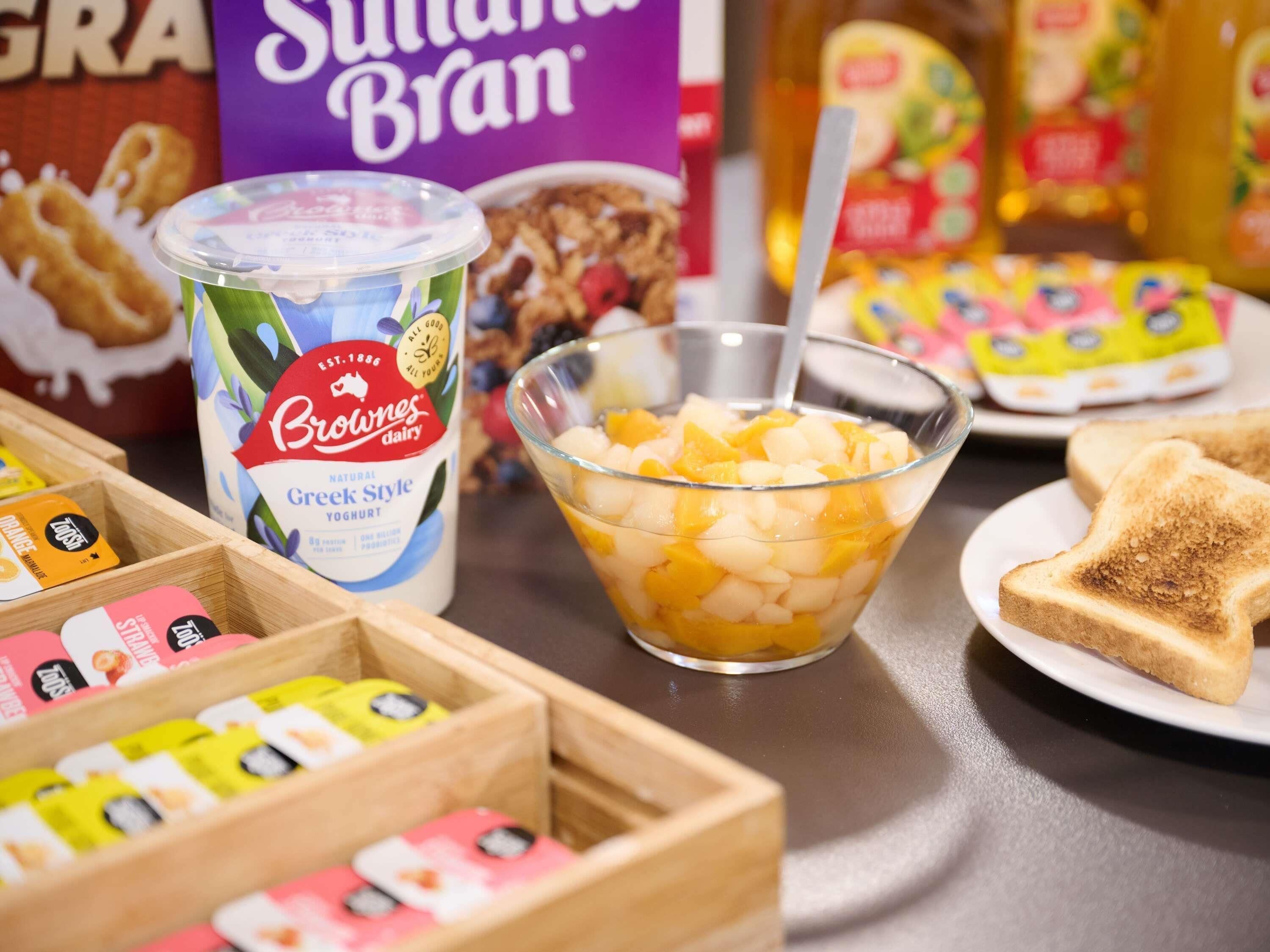 Een ontbijttafel met fruit, yoghurt en een sneetje toast.