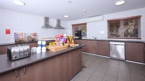 A modern kitchen with a built-in toaster, a coffee machine, and a dishwasher. - Ibis Budget Perth Airport (Redcliffe)