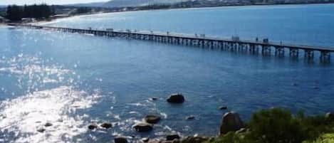 A pier extending into a calm body of water with a clear sky above.