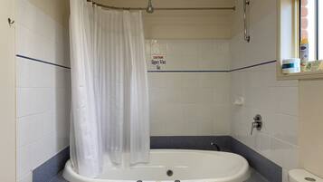 A bathroom with a bathtub, a shower curtain, and a caution sign.
