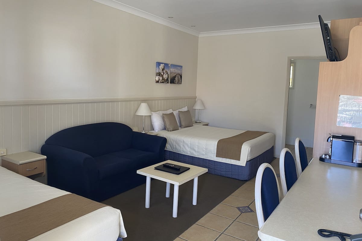 A hotel room with a bed, a sofa, a small table, and a desk with chairs.