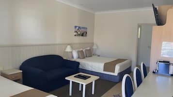 Een hotelkamer met een bed, een bank, een kleine tafel en een bureau met stoelen.