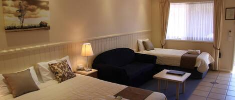 Une chambre d’hôtel avec deux lits, un canapé, une petite table et un tableau au mur.