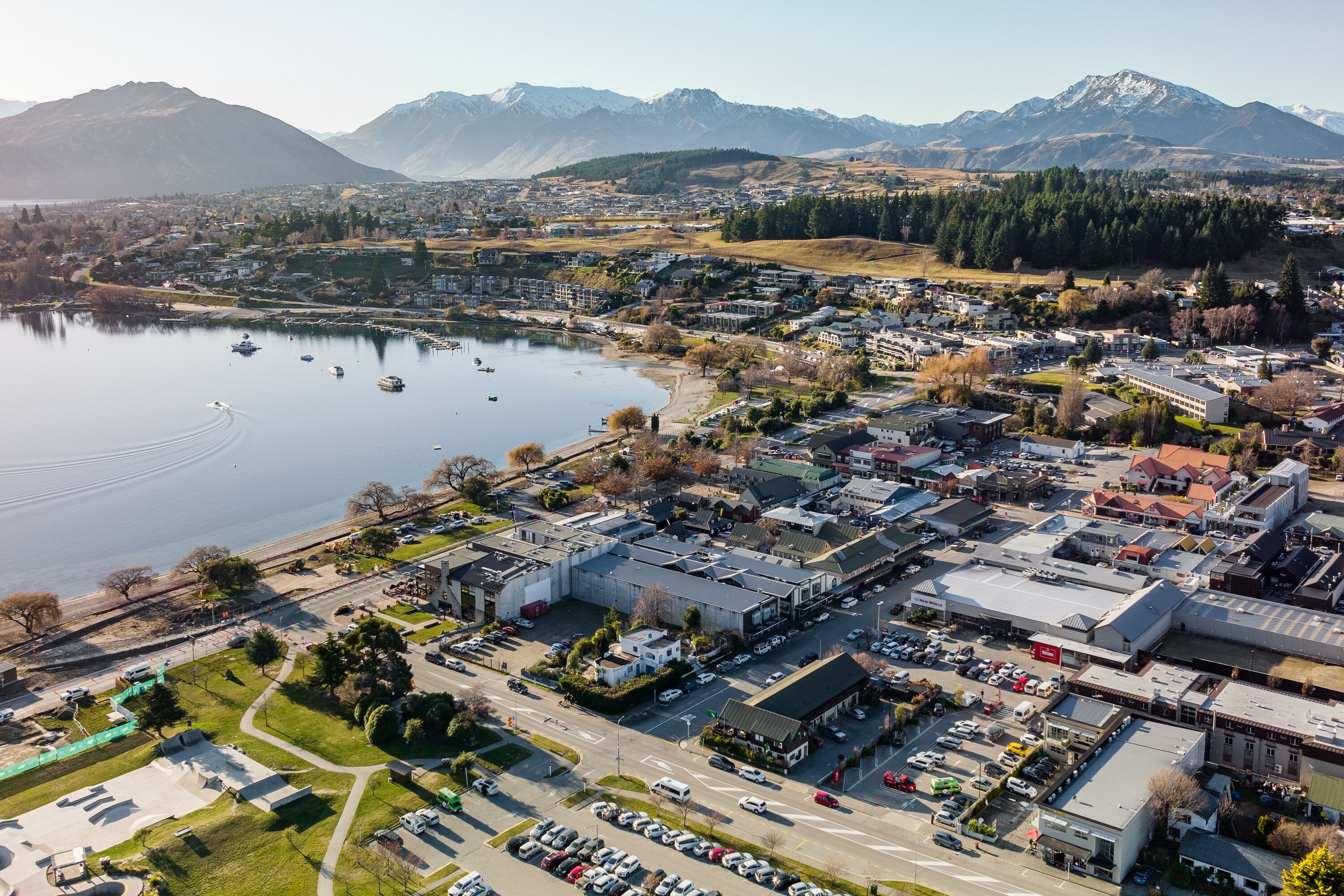 Eine Vogelperspektive einer Stadt mit einem See, Bergen im Hintergrund und einer Mischung aus Wohn- und Geschäftsgebäuden.