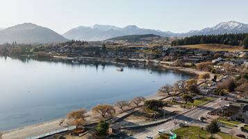 An aerial view of a lakeside town with residential buildings, a marina, and mountains in the background.