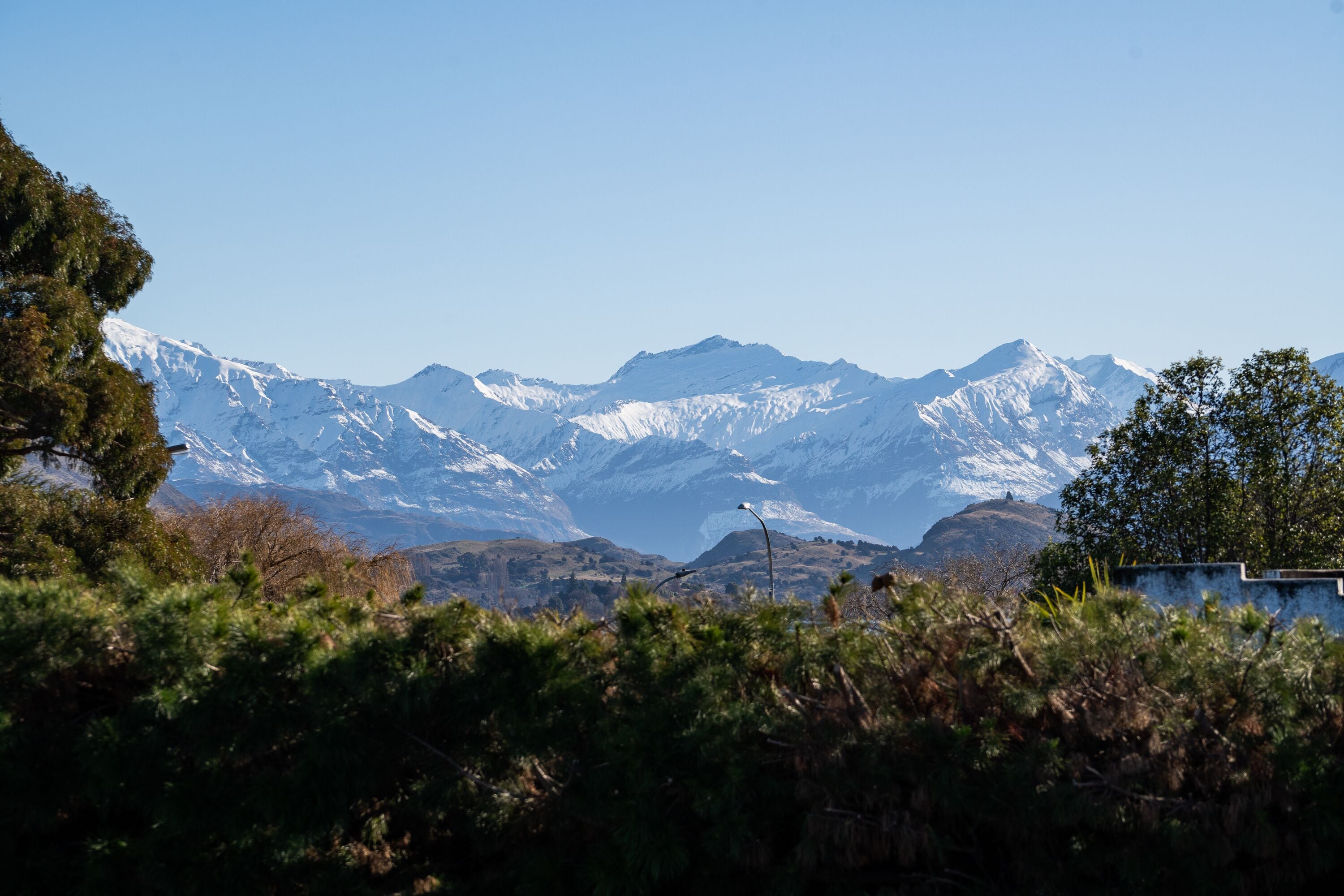 Un paisaje montañoso con picos nevados y cielo despejado.
