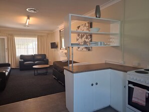 Un espacio habitable compacto con kitchenette, un sofá, una mesa de comedor y un televisor.