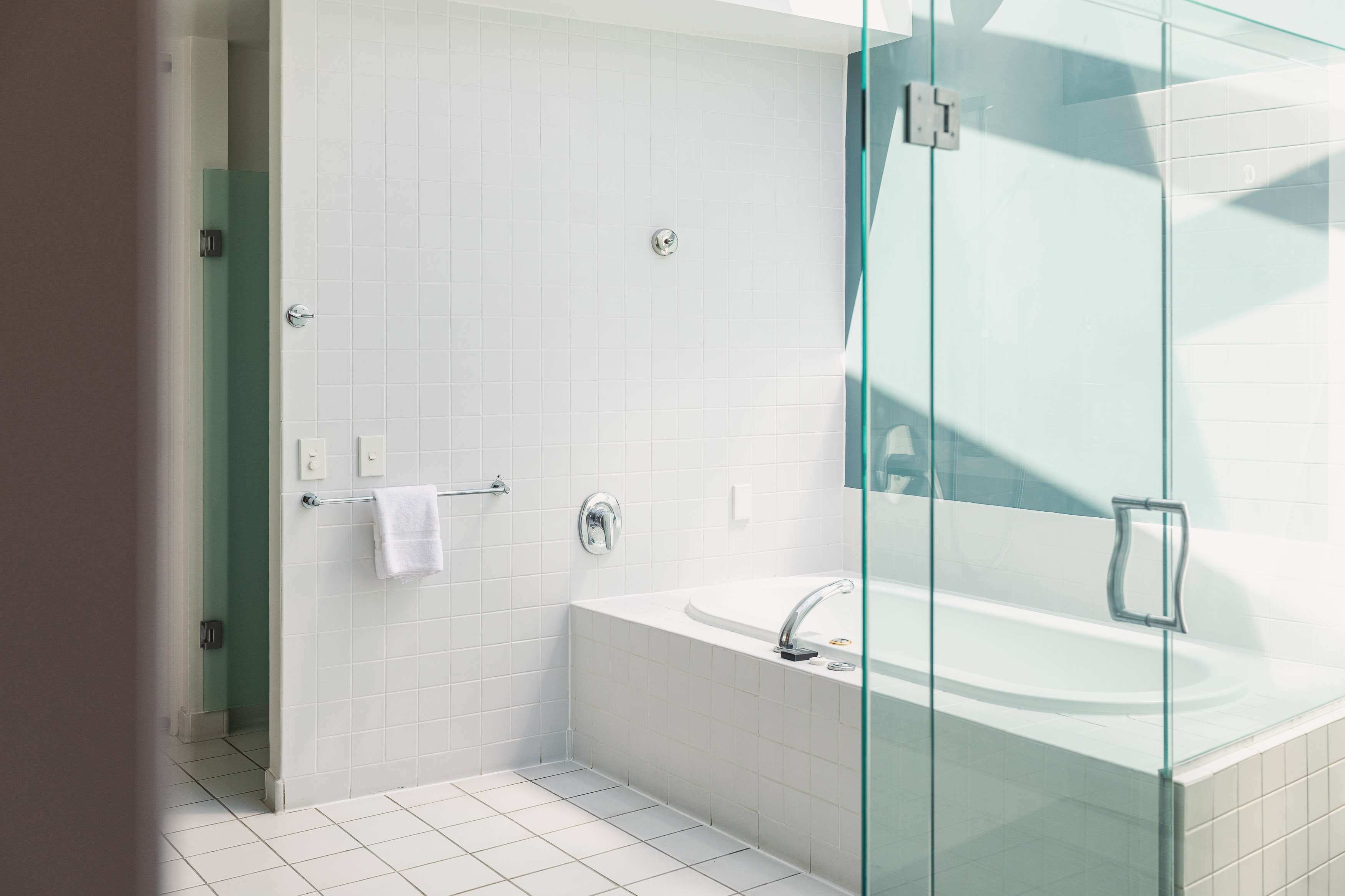 A modern bathroom with a glass-enclosed shower, a freestanding bathtub, and white tiled walls.