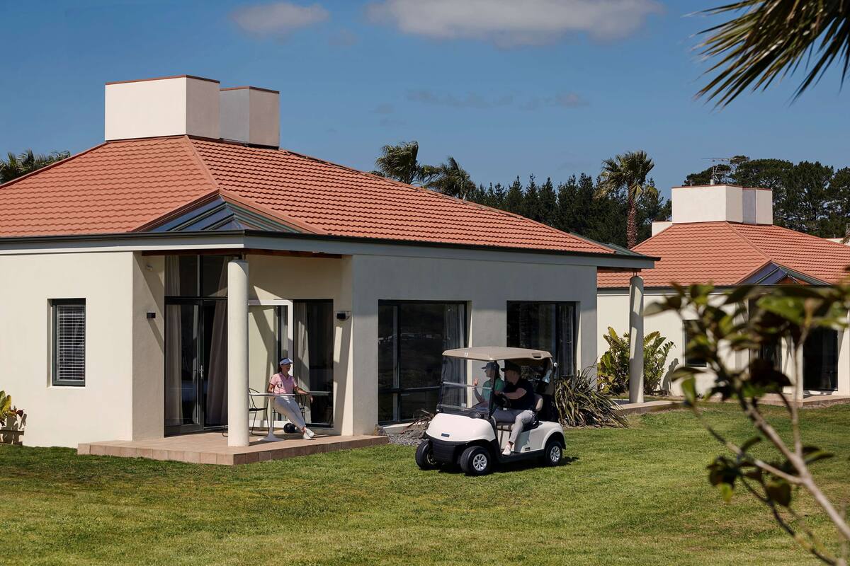A modern house with a red-tiled roof, a covered patio, and a lawn.