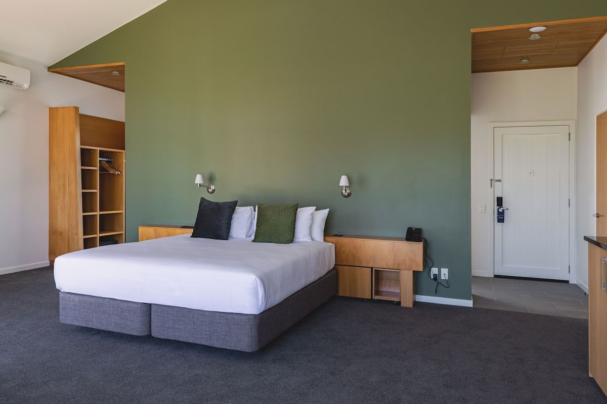 A bedroom with a bed, bedside tables, a wardrobe, and a door.
