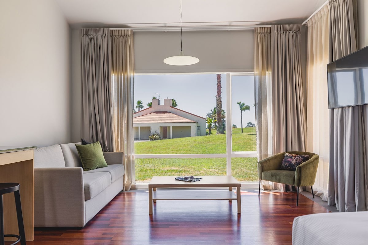 A modern living room with a sofa, armchair, coffee table, and a TV.