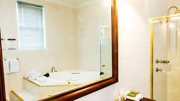 A bathroom with a large mirror, a bathtub, a shower, and a sink with gold fixtures.