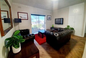 Un salón con un sofá de cuero, una mesa de centro, un televisor y un ventanal con vistas.