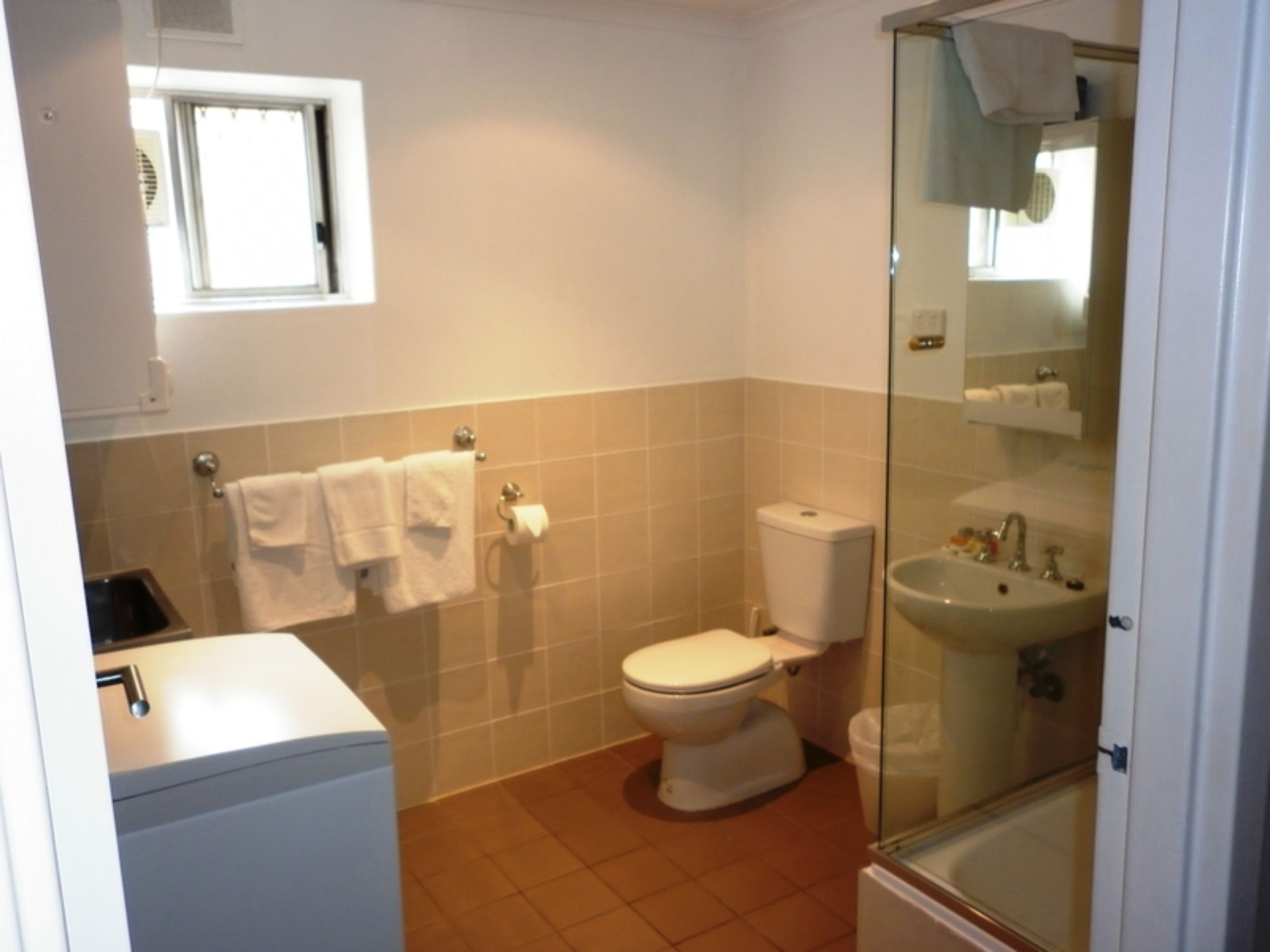 A bathroom with a toilet, sink, and a window.