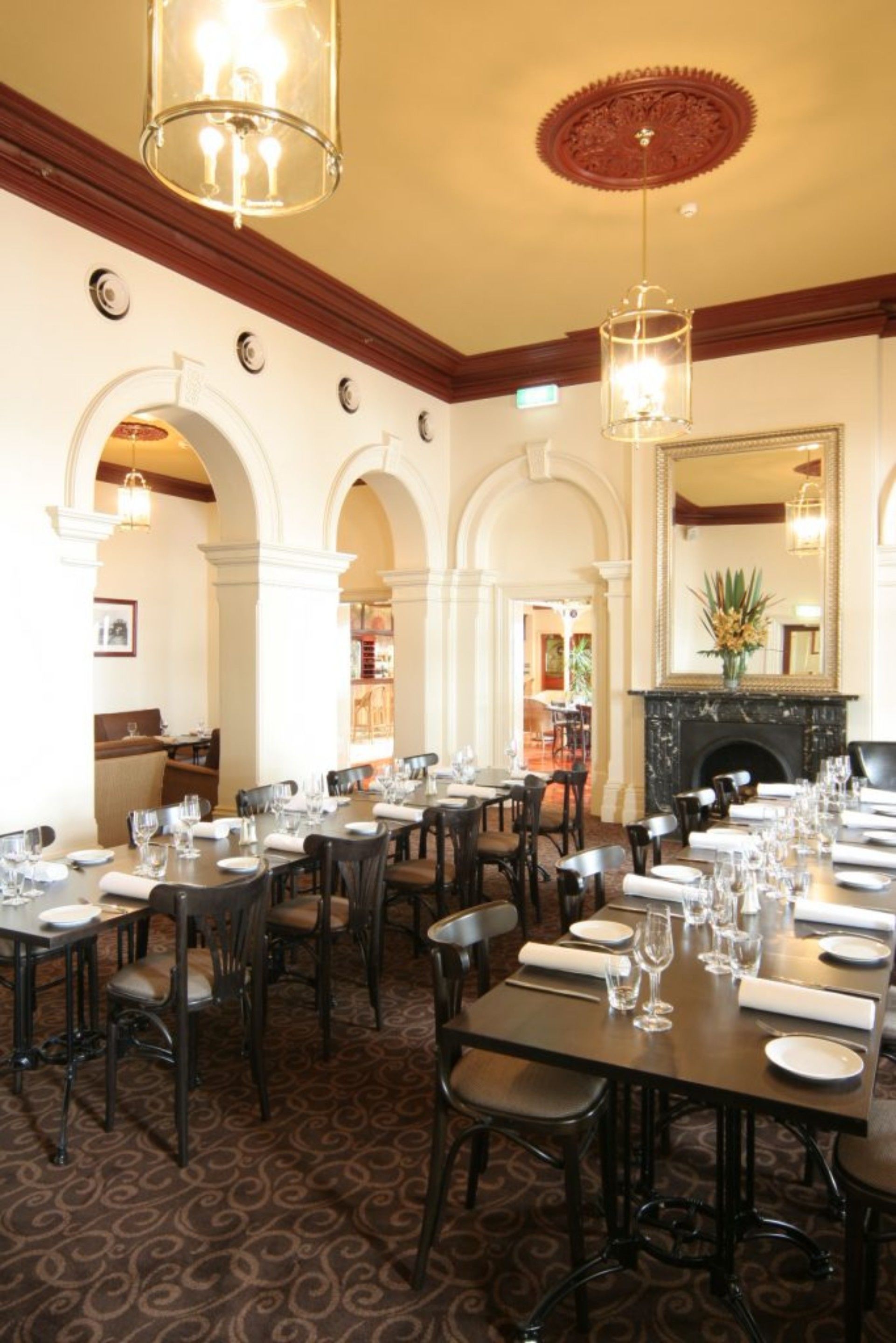A formal dining room with multiple tables set for service, a fireplace, and a decorative ceiling.