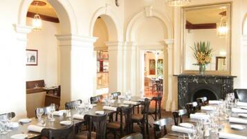A formal dining room with multiple tables set for service, a fireplace, and a decorative ceiling.