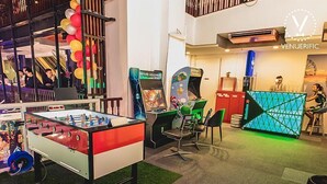 Een hotellobby met een tafelvoetbaltafel, speelautomaten en een kinderspeelruimte.
