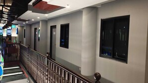 Een hotelgang met een houten balustrade, een trap en een rij deuren en ramen.