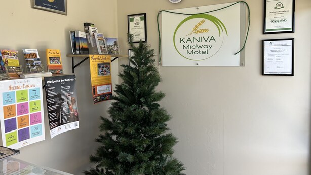 A reception area with a Christmas tree, framed certificates, a welcome sign, and informational posters. - Kaniva Midway Motel (Kaniva)