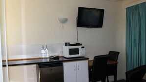 A compact kitchenette with a microwave, a small refrigerator, and a dishwasher. A flat-screen TV is mounted on the wall above the counter. - Kaniva Midway Motel (Kaniva)