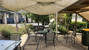 An outdoor patio with a table and chairs, a grill, and a covered area with a canopy. - Kaniva Midway Motel (Kaniva)