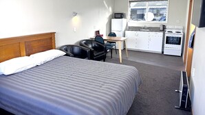 Ein Hotelzimmer mit Bett, Schreibtisch, Mikrowelle, Kühlschrank und Herd.