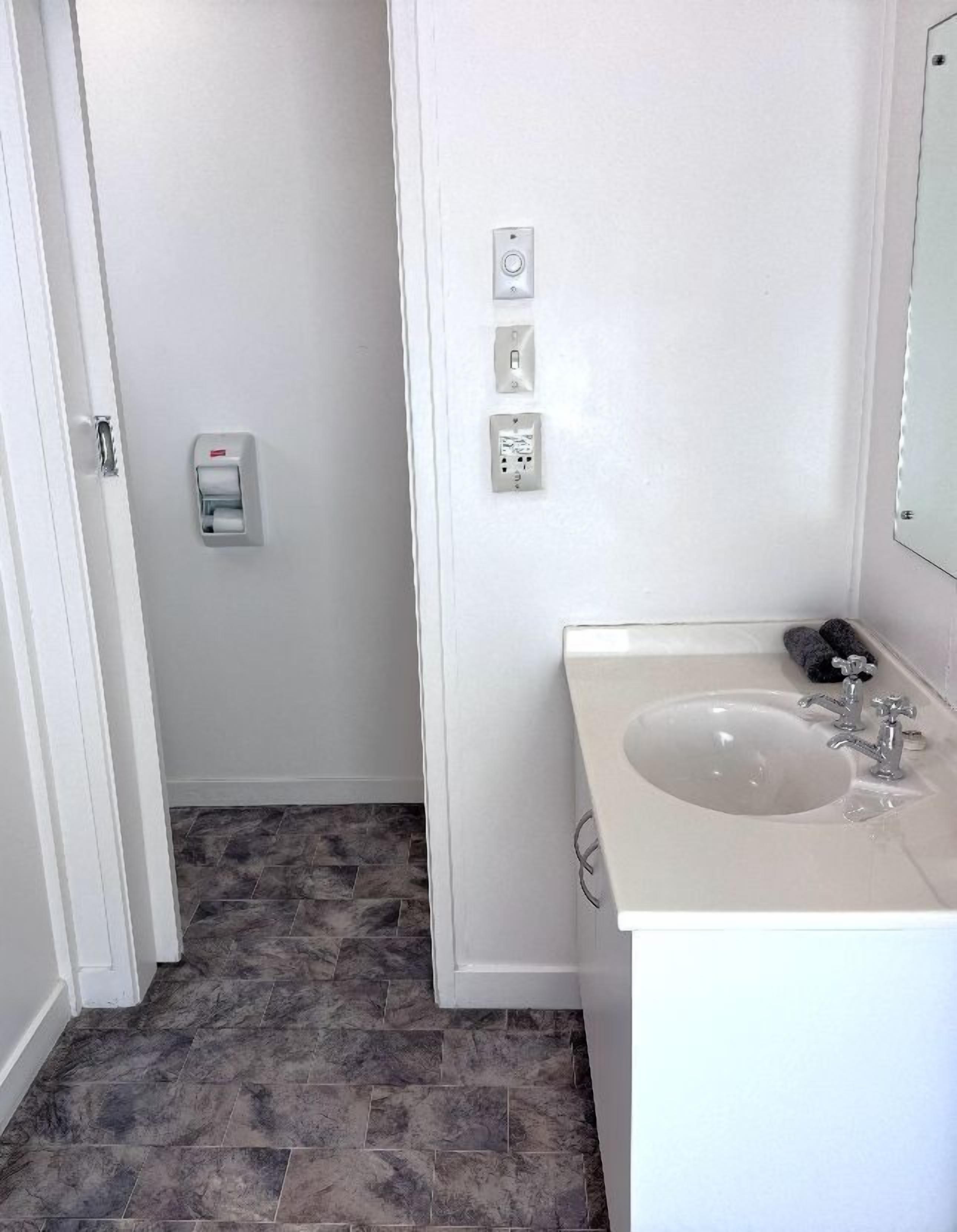 Un bagno con lavandino, specchio e porta carta igienica a muro.
