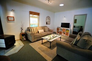 Una sala de estar con sofá, mesa de centro, televisor y chimenea.
