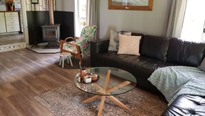 Una sala de estar con chimenea, un sofá, una mesa de centro de vidrio y un cuadro en la pared.