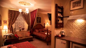 Ein Schlafzimmer mit Bett, Nachttisch, Lampe und einer kleinen Küchenzeile.
