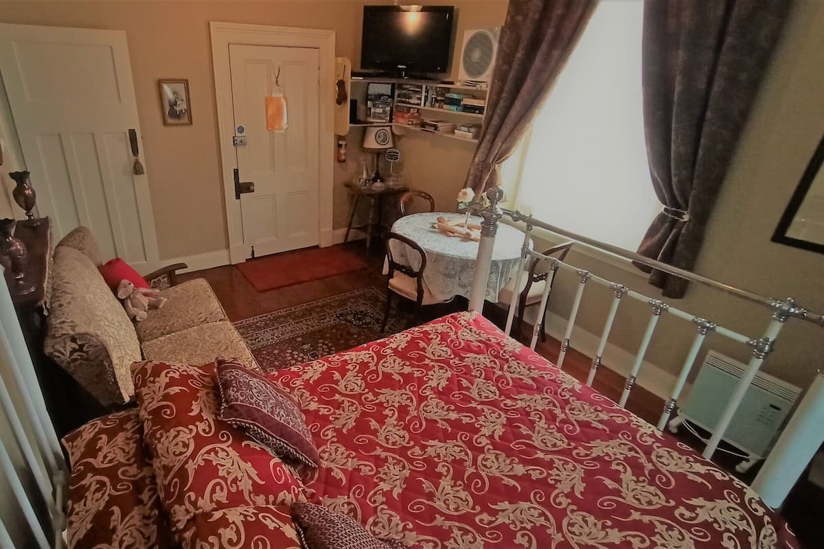 Ein Schlafzimmer mit Bett, Stuhl, kleinem Tisch und Fernseher.