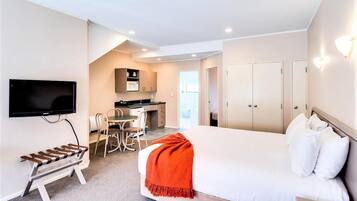 A hotel room with a bed, a TV, a desk with a chair, a microwave, and cabinets.