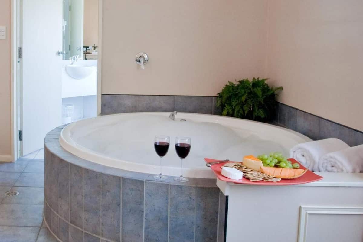 A modern bathroom with a freestanding bathtub, a towel rack, and a small plant.