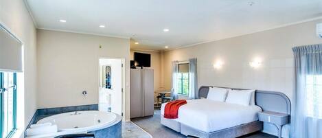 Una habitación de hotel con cama, escritorio, silla, bañera y televisor.