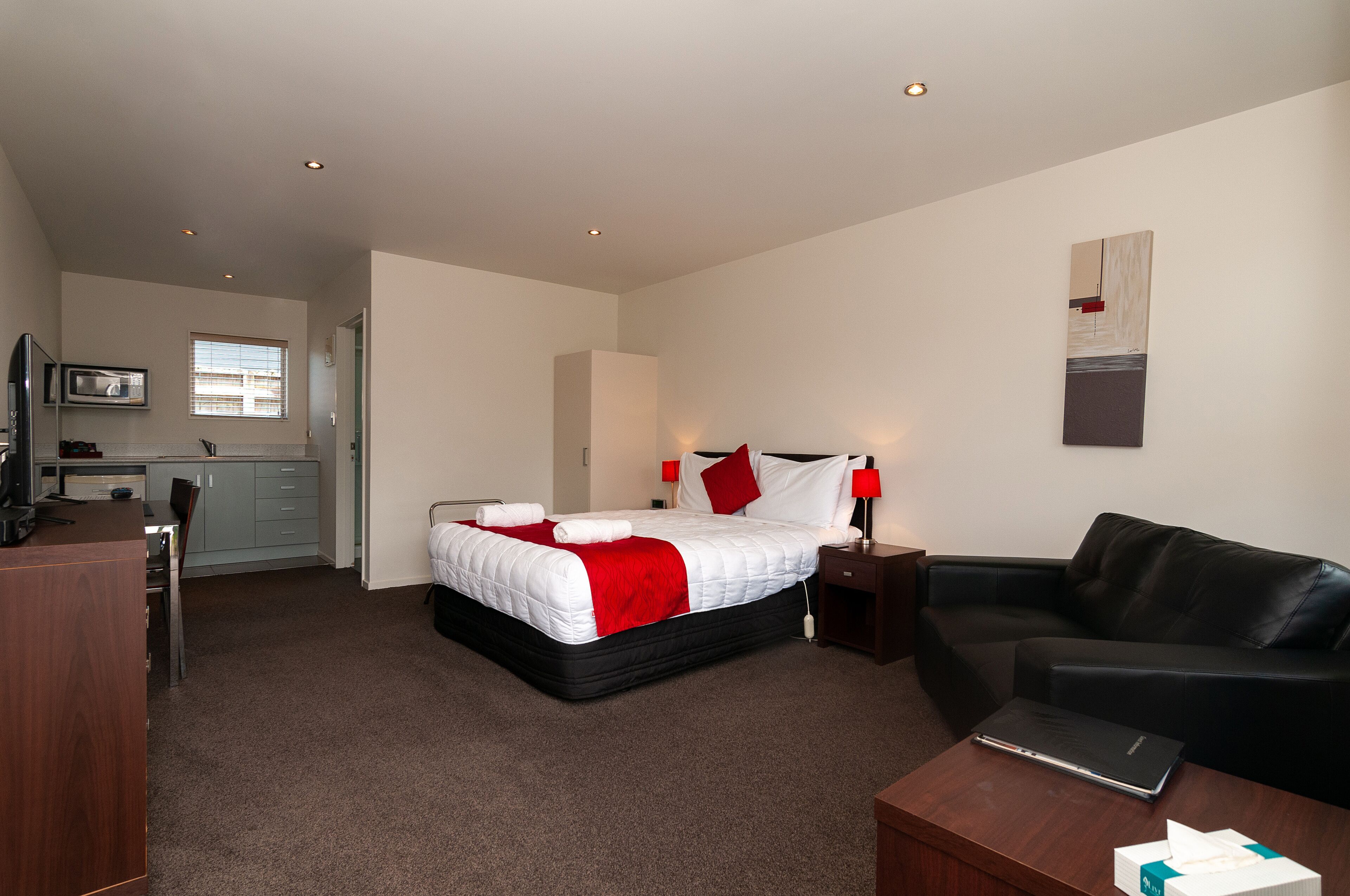 Une chambre d’hôtel avec un lit, un bureau, une chaise, un canapé et un téléviseur.