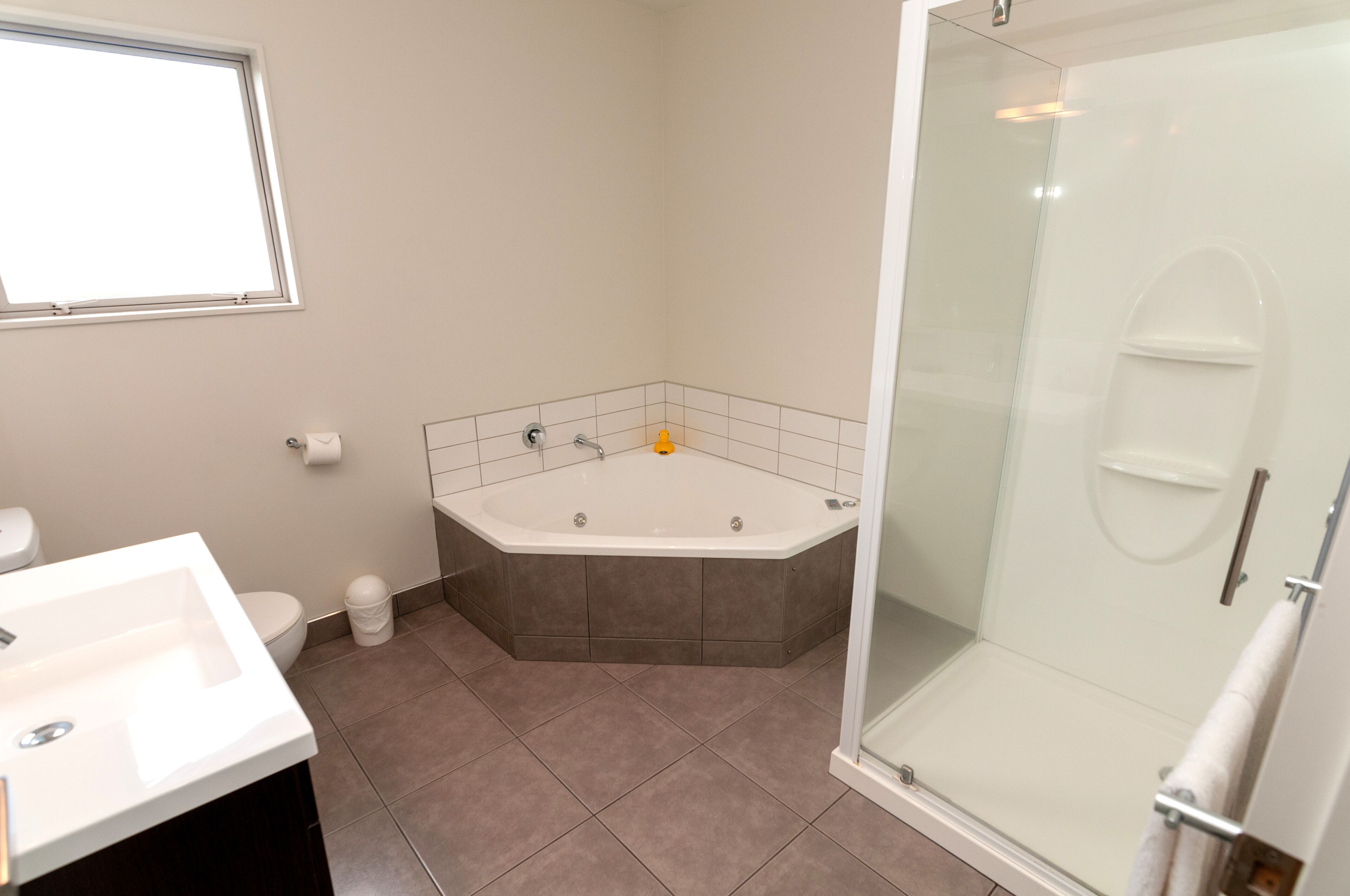 A modern bathroom with a bathtub, a glass-enclosed shower, a toilet, and a sink.