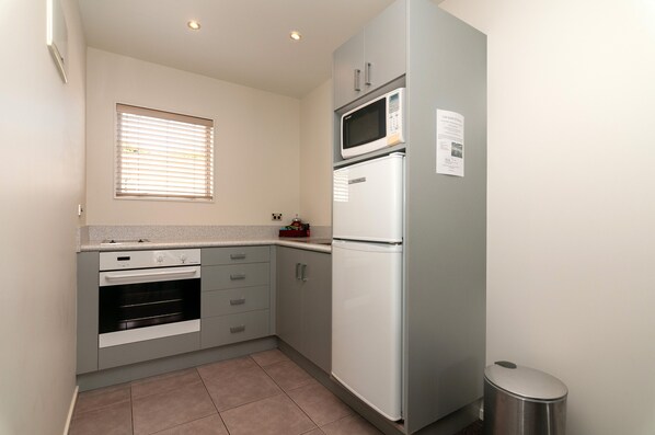 A compact kitchen with a built-in oven, microwave, and refrigerator.