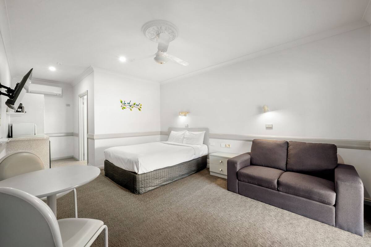 Una habitación de hotel moderna con cama, sofá, una mesita y una silla.