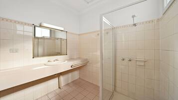 Un baño con ducha de vidrio, lavamanos con espejo y paredes de azulejos.