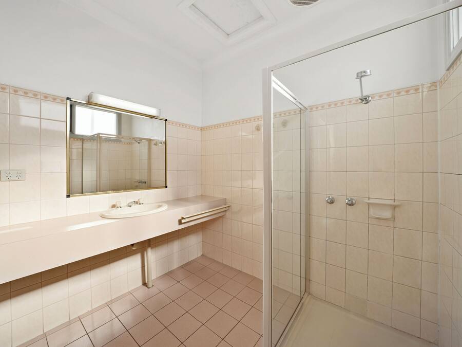 Un baño con ducha de vidrio, lavamanos con espejo y paredes de azulejos.