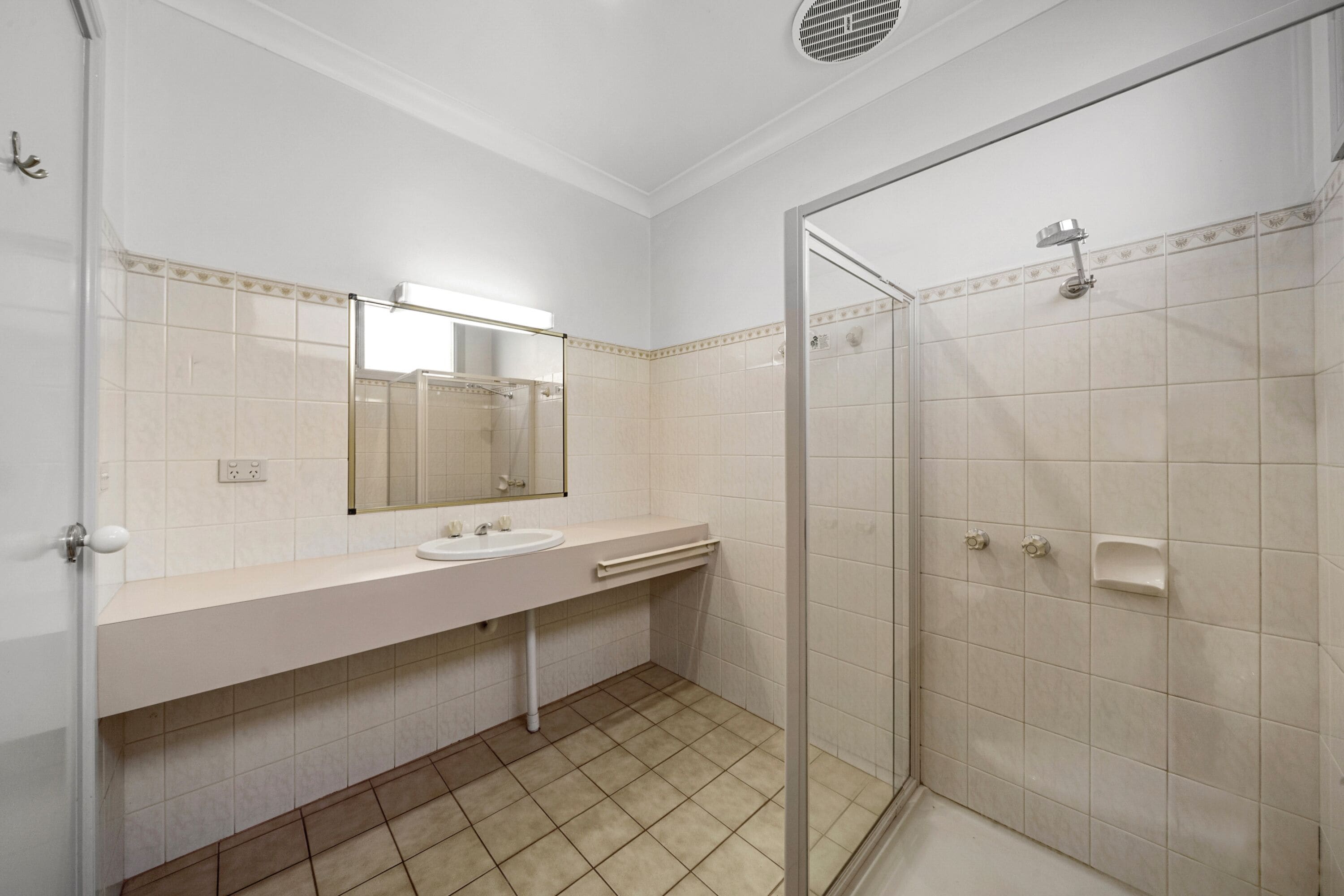 Un baño con lavamanos blanco, espejo y ducha.
