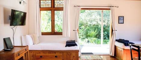 A room with a bed, a television, a desk, and a window with curtains.