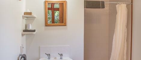 A bathroom with a wooden ceiling, a white sink, a mirror, and a shower curtain.