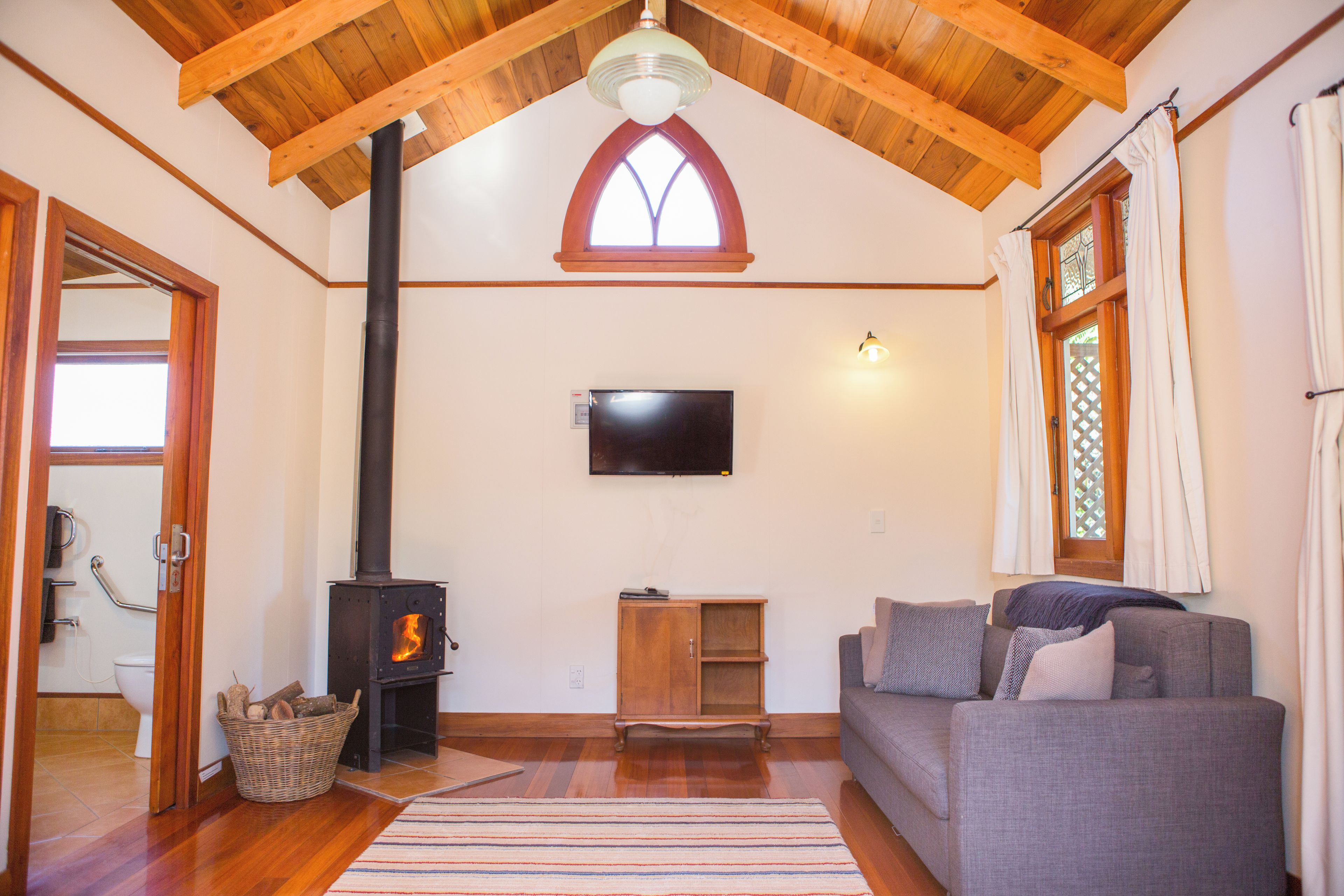 Ein gemütliches Wohnzimmer mit Kamin, Holzbalken, Fernseher und einer Couch.